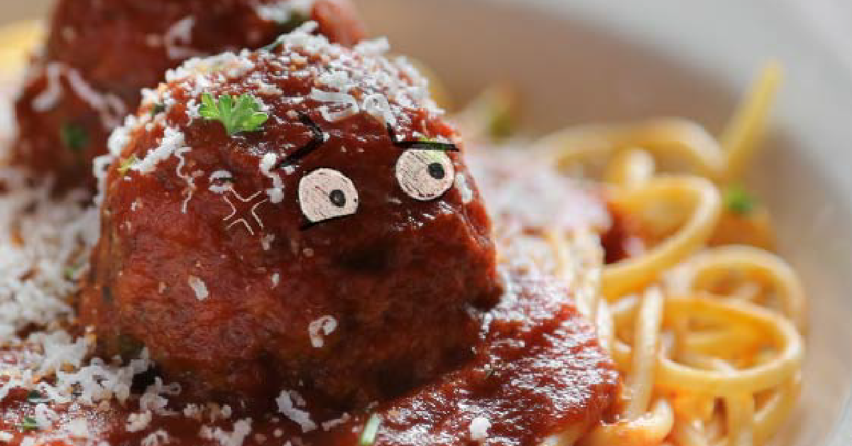Meatball with eyes on top of sauce and pasta.