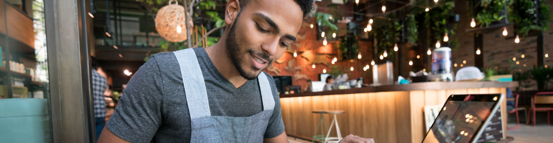 Image of a male employee leaning over a counter in a restaurant.