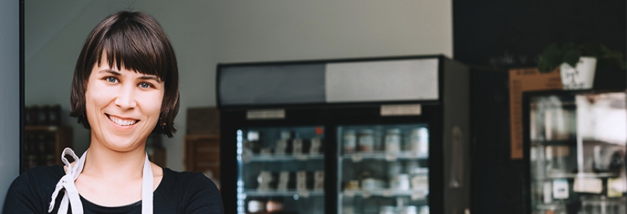 Image of a female cafe worker smiling at the camera in a cafe.