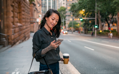 Woman on a city sidewalk looking at her mobile phone